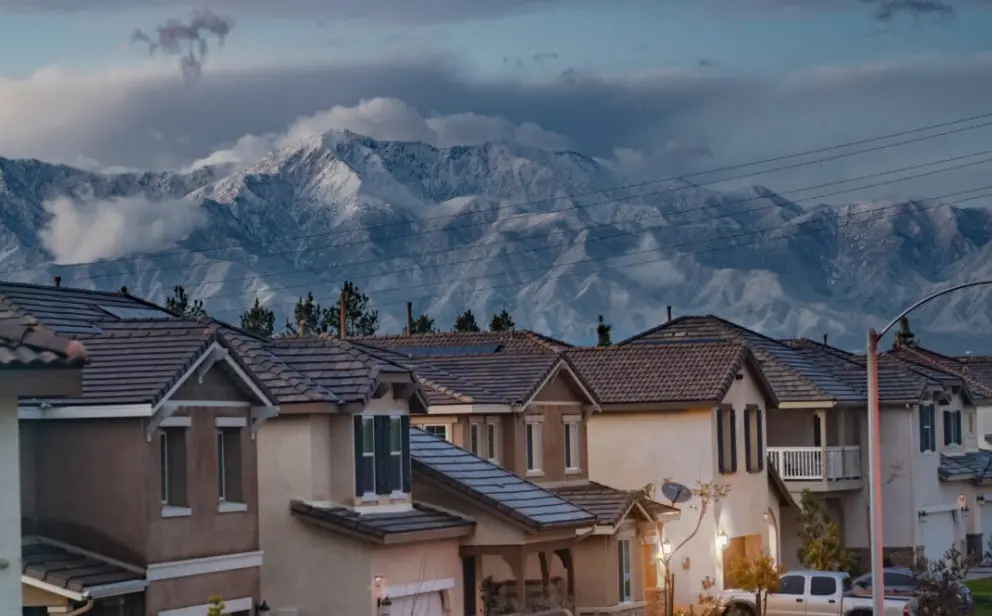 Row of houses with tile roofs in front of snow-capped mountains