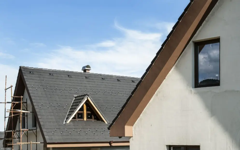 Dark shingle roof with a dormer on a house under construction